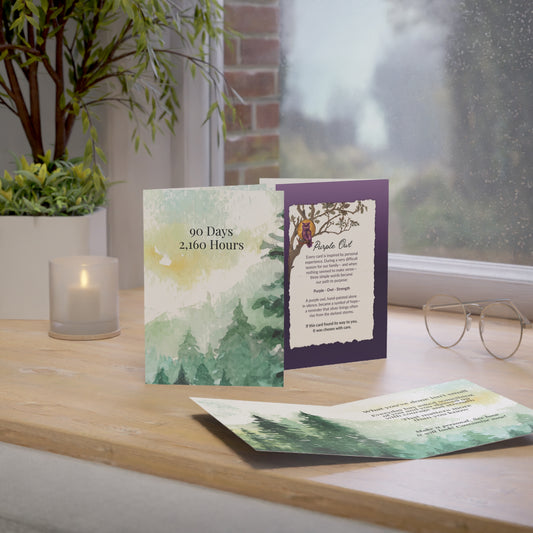 Greeting cards on a wooden surface with a window and plant in the background